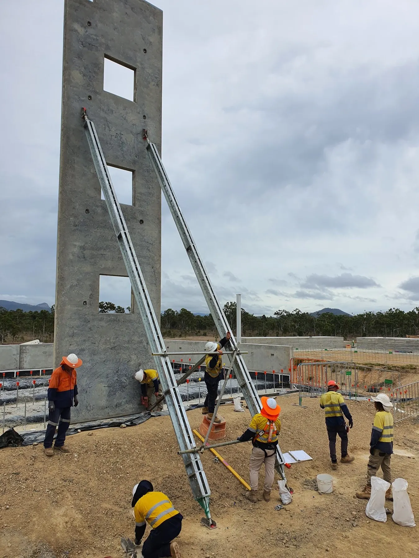 Crew propping a tilt panel with braces on a construction site